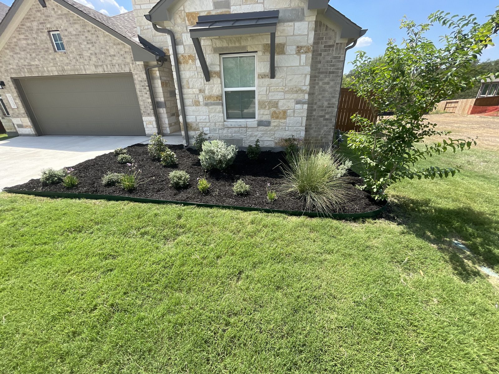 New landscape bed with fresh mulch and plantings installed by Gonzales Landscaping
