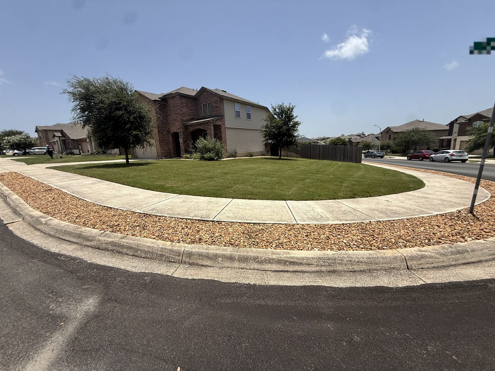 Freshly mowed round corner-lot lawn by Gonzales Landscaping