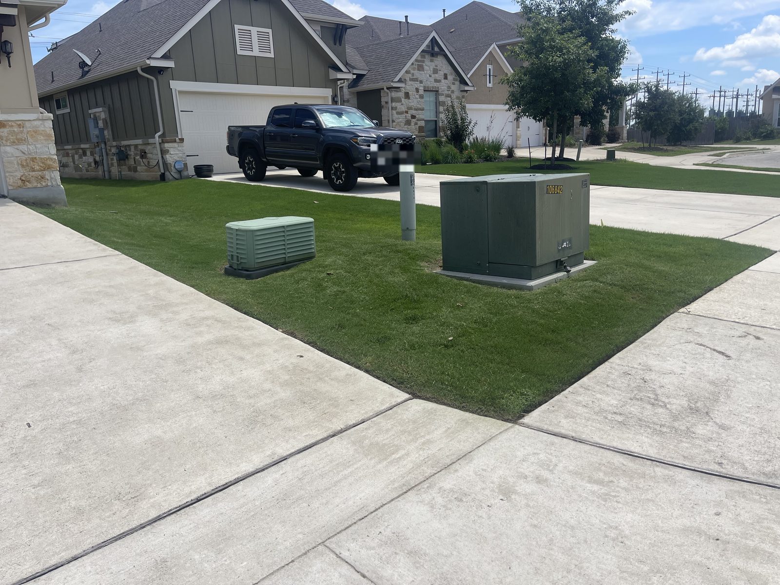Mowed lawn around utility equipment in a Cibolo, TX yard by Gonzales Landscaping