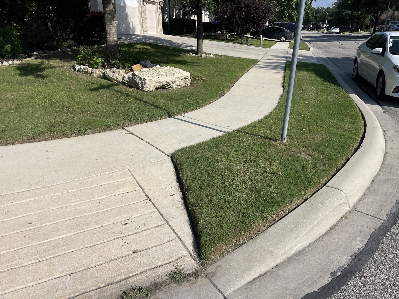 Freshly mowed corner-lot lawn along a sidewalk in Cibolo, TX by Gonzales Landscaping