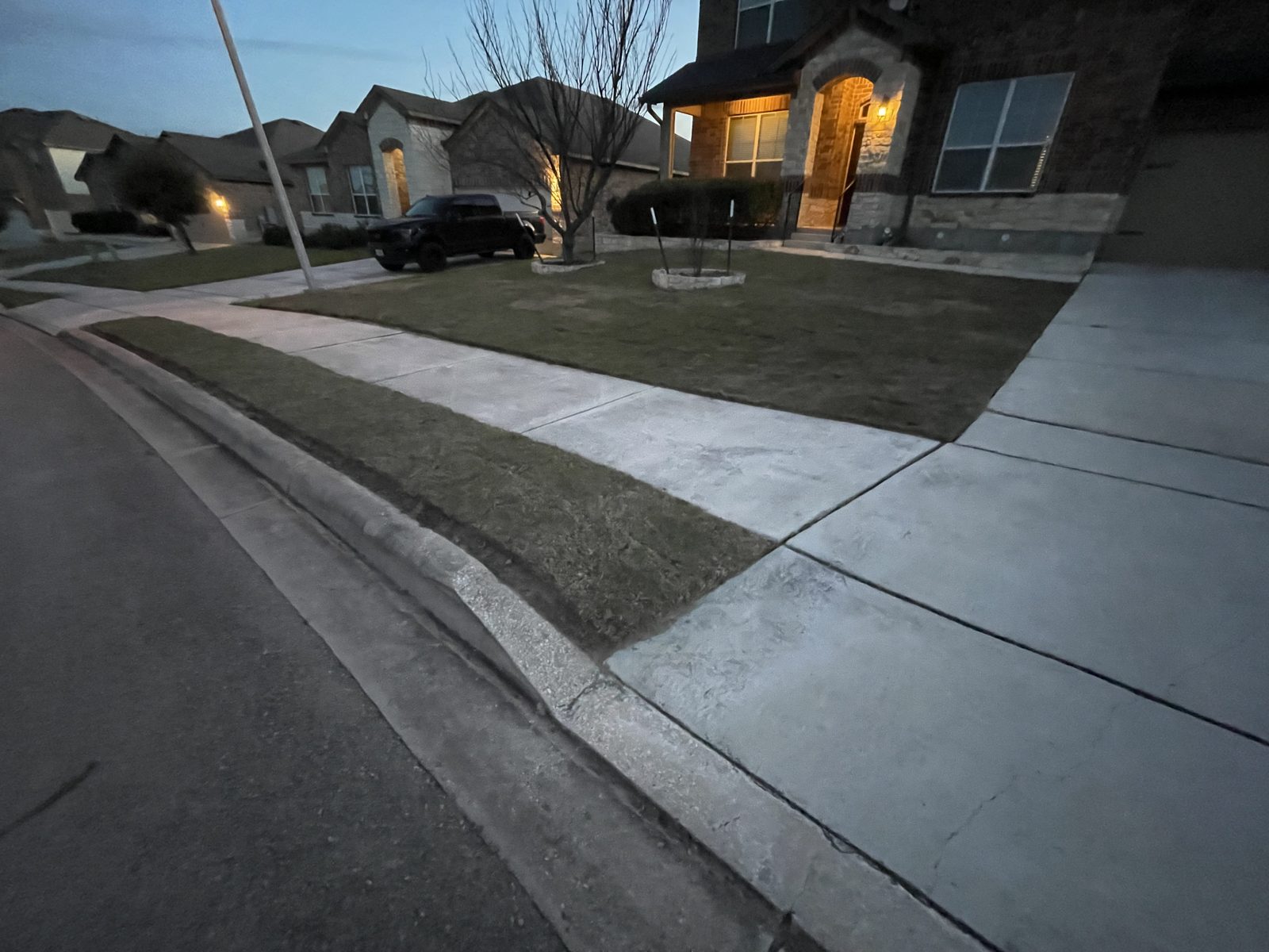Freshly installed sod along a sidewalk and curb at dusk in Cibolo, TX by Gonzales Landscaping
